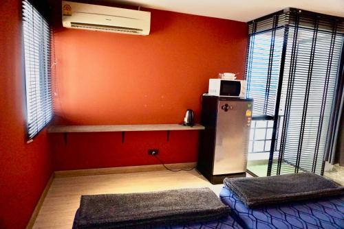 a red room with a refrigerator and a microwave at Silom Soi 3 Hash Apartment hip and funky with rooftop view in Bangkok