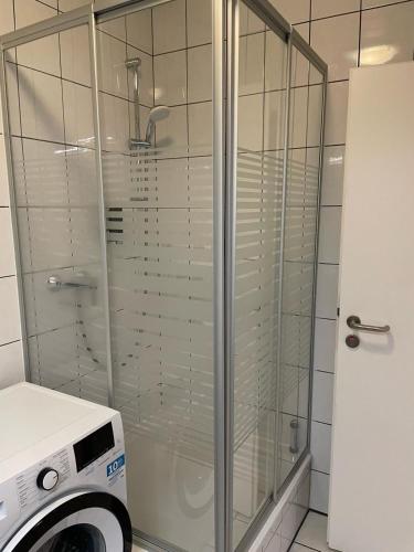 a glass shower in a bathroom with a washing machine at NP Hotel Königshof in Dortmund