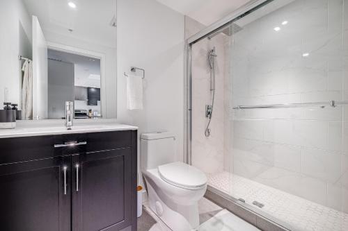 La salle de bains blanche est pourvue d'une douche et de toilettes. dans l'établissement Westview Luxury Suites, à Ottawa