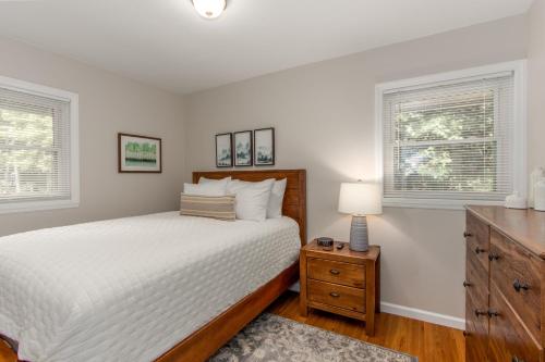 a bedroom with a bed and a dresser and two windows at State College Getaway in State College