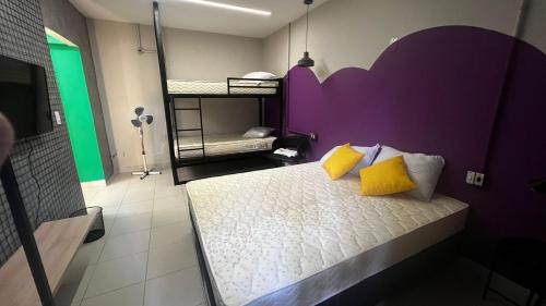 a bedroom with a bed with a purple headboard and yellow pillows at Belô Hostel in Belo Horizonte