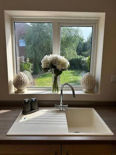 eine Küchenspüle mit einer Vase aus Blumen im Fenster in der Unterkunft Bonningtons - Charming 2 Bed Property In Brentwood in Shenfield