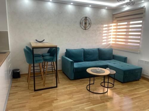 a living room with a blue couch and two stools at Apartman Plavi bor in Zlatibor
