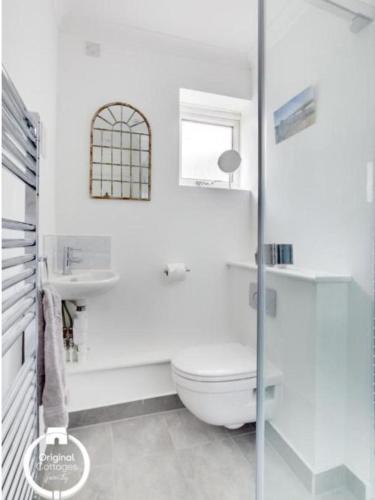 a white bathroom with a toilet and a window at The Heart of Rye in Rye
