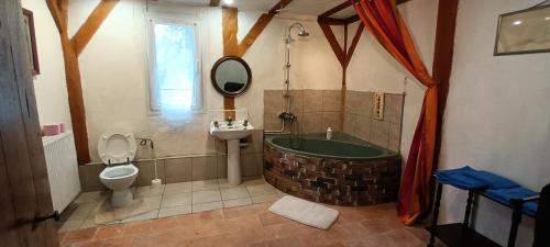 a bathroom with a tub and a toilet and a sink at La suite du Bûcheron in Laharie