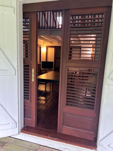 a wooden door leading into a room with a table at La villa créole de Vaughenlieu in Lamentin