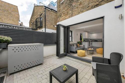 a patio with a table and chairs and a living room at Sleek 1 Bed Haven with Private Outdoor Space in London