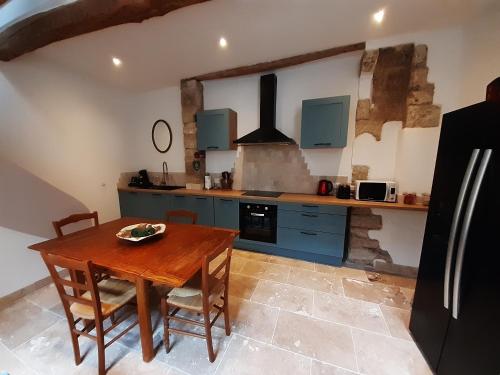 une cuisine avec des placards bleus et une table en bois dans l'établissement Village house on 3 floors, à Saint-Thibéry