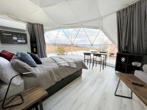 1 dormitorio con 1 cama y 1 mesa con sillas en Port Wade Glamping Domes, en Victoria Beach 