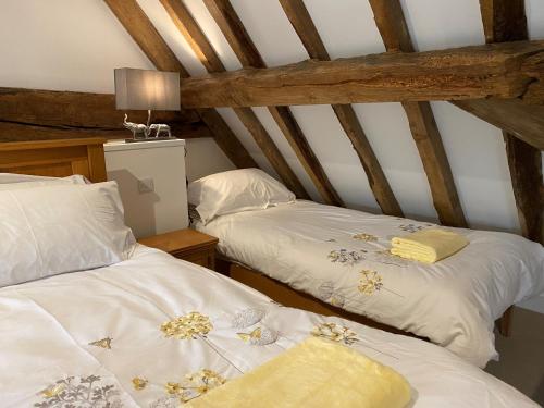 two beds in a room with wooden beams at Monarchs View Farmstay in Michelmersh