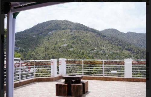 a bench on a balcony with a view of a mountain at Maan Cottages in Rāmgarh