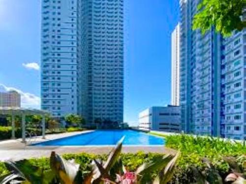 una gran piscina en una ciudad con edificios altos en GRASS RESIDENCES PROMENADE SM North Edsa QC en Manila