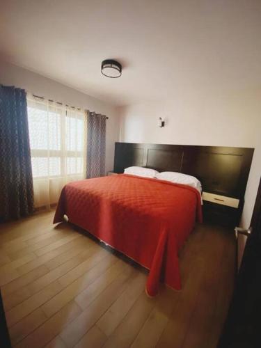 a bedroom with a red bed and a window at Apartamento #10 Portal de Occidente in Quetzaltenango