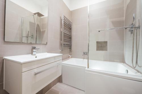 a white bathroom with a sink and a tub and a shower at Stylish & Modern London Apartment in Honor Oak in London