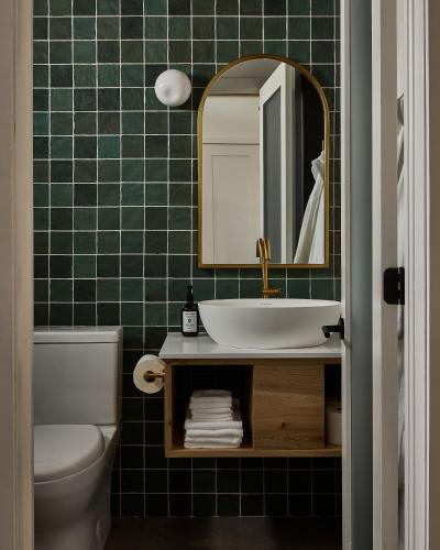 a green tiled bathroom with a sink and a mirror at The Smith Hotel in Kingston