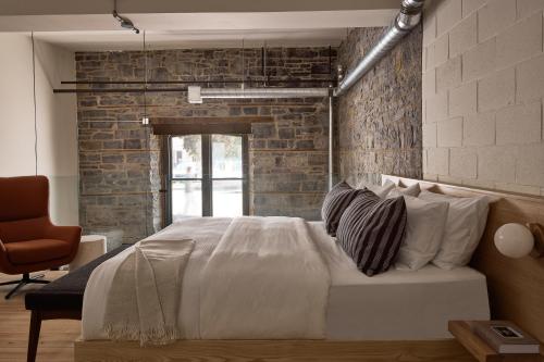 um quarto com uma cama branca e uma parede de tijolos em The Smith Hotel em Kingston