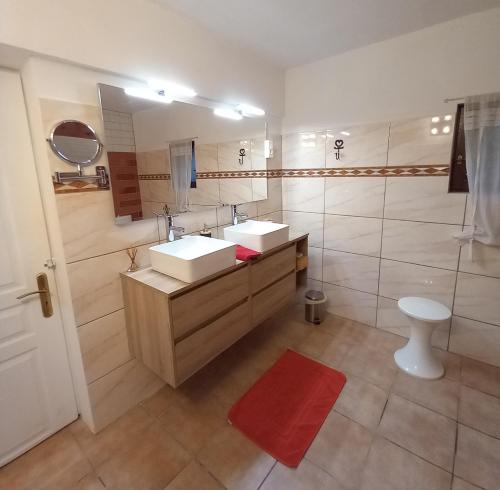 La salle de bains est pourvue de 2 lavabos et d'un tapis rouge. dans l'établissement La Bastide de l'Olivier, au Muy