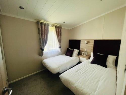 two beds in a small room with a window at Enzo's Lodge with Hot Tub in York