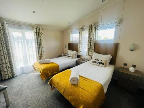 a hotel room with two beds with yellow sheets at Waterside Retreat With Hot Tub in Pocklington
