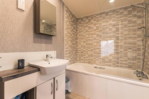 a bathroom with a sink and a bath tub at Waterside Retreat With Hot Tub in Pocklington