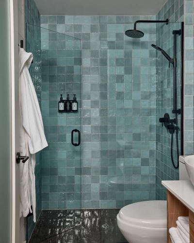 a blue tiled bathroom with a toilet and a shower at The Smith Hotel in Kingston