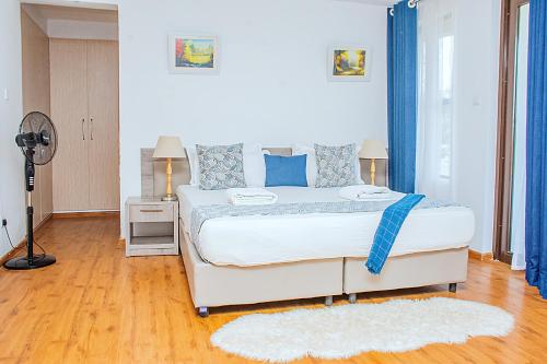 a bedroom with a large white bed with blue pillows at Casa Misa Riverside Duplex in Nairobi