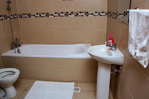 a bathroom with a tub and a sink and a toilet at Casa Misa Riverside Duplex in Nairobi