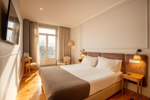 um quarto de hotel com uma cama e uma janela em Memoria Porto FLH Hotels no Porto
