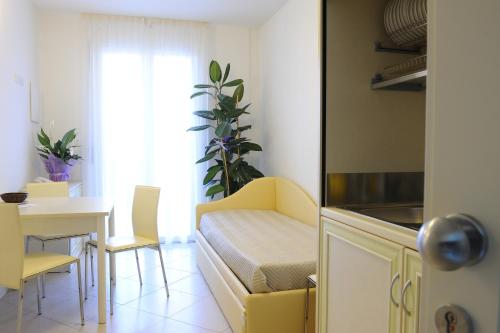 una cucina con tavolo e un divano giallo in una camera di Residence Suite Smeraldo a Riccione