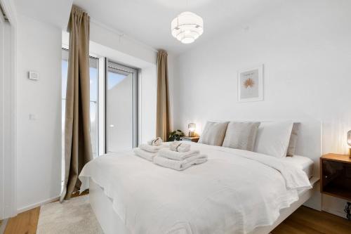 a white bedroom with a bed with towels on it at Penthouse paradise on 39th floor in Aarhus