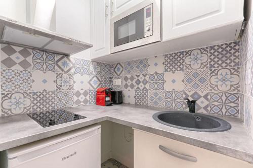 une cuisine avec un évier et un micro-ondes dans l'établissement Montmartre/Natier : Cosy Studio 2P, à Paris