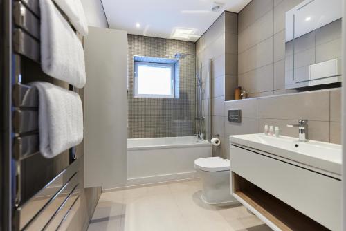 a bathroom with a toilet and a sink and a tub at The Wembley Park Wonder - Charming 2BDR Flat with Balcony in London