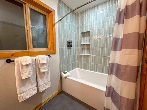 a bathroom with a tub and a shower with towels at Fern Hollow in Glacier