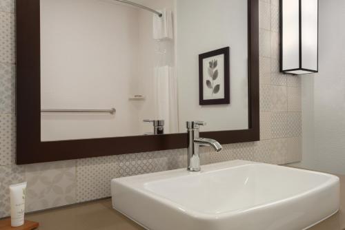 a bathroom with a white sink and a mirror at Country Inn & Suites by Radisson, Oklahoma City - Bricktown, OK in Oklahoma City