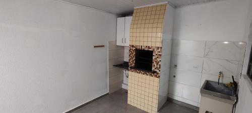 uma cozinha com paredes brancas e uma parede de azulejos em Casa no Country em Cascavel