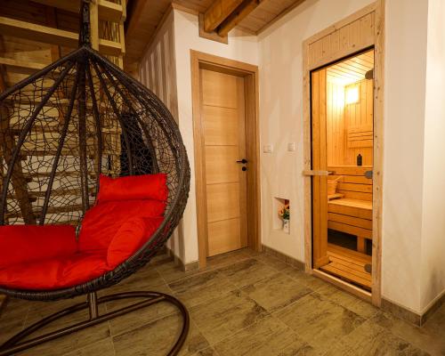 a hanging chair with red pillows in a room at Vila Marija HP in Han Pijesak