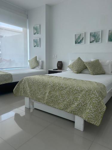 a white bedroom with two beds and a window at Apartamento de lujo en Morros Ultra in Cartagena de Indias