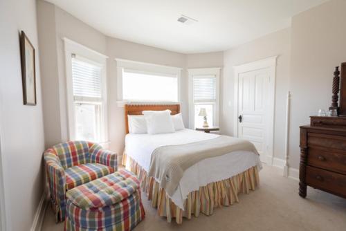 a white bedroom with a bed and a chair at Clifton House - Big River South - Mississippi River Views, Queen Suite in Natchez
