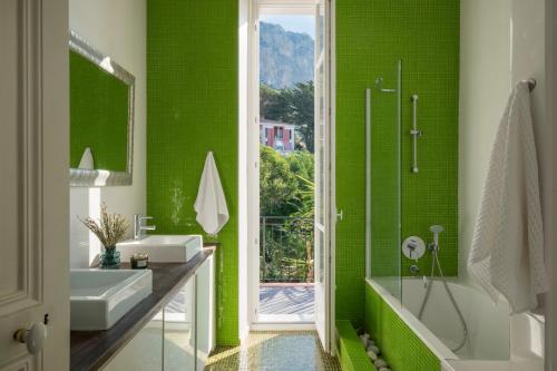 a green bathroom with a tub and a sink at Villa Fantaisie in Menton