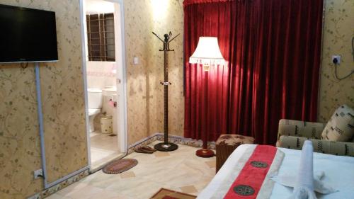 a bedroom with a red curtain and a room with a tv at Babylon Hotel & Serviced Apartment in Dhaka
