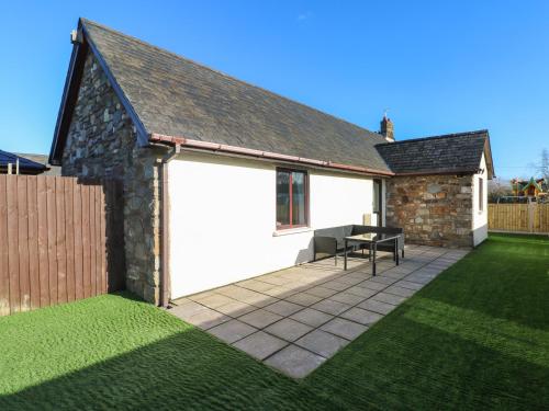 a white garage with a table on a lawn at The Old Well Bungalow - Ty Mawr Farm in Cardiff