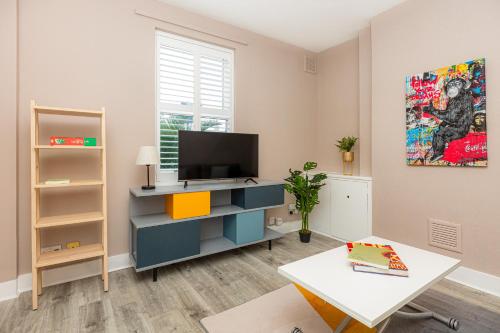 a living room with a tv and a table at Renovated 3BR wgarden in Stratford, 1min to Train in London