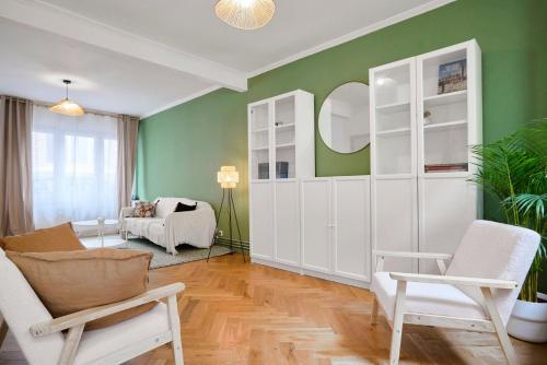 una sala de estar con paredes verdes y muebles blancos. en Charmante maison 3 chambres avec jardin., en La Madeleine