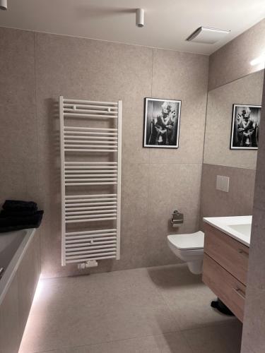 a bathroom with a sink and a toilet and two pictures at MARKT LIFE HOME APPARTMENTS in Lutherstadt Wittenberg