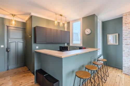 une cuisine avec un comptoir et des tabourets dans une pièce dans l'établissement Charming 2 bedroom apartment - Old Lille, à Lille