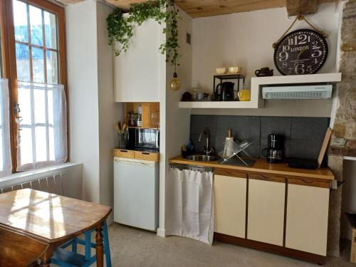 a kitchen with white cabinets and a table and a clock at Le patio in Oloron-Sainte-Marie