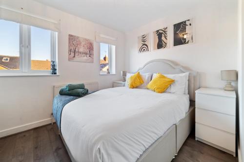 een slaapkamer met een groot wit bed met gele kussens bij Luxury house close to city center sleeps 6 with free parking in Leicester
