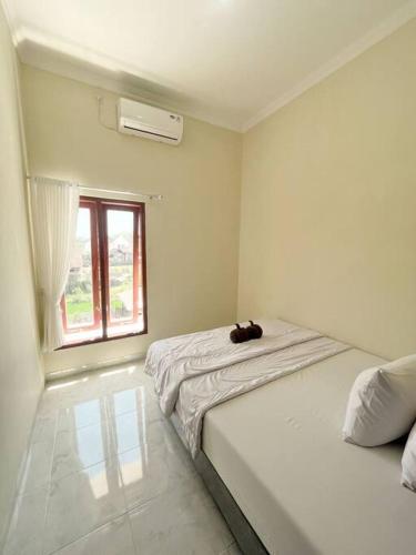 ein weißes Zimmer mit einem Bett und einem Fenster in der Unterkunft Homestay Kamar Tamu Sitimulyo in Karanggayam