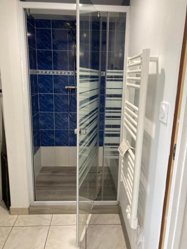 La salle de bains est pourvue d'une douche en verre et de carrelage bleu. dans l'établissement Rose des sables R d c, à Jullouville