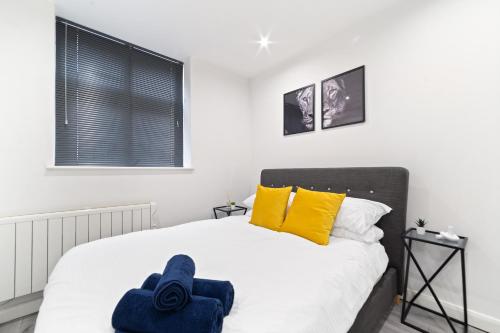 a bedroom with a bed with yellow pillows at Modern Apartment with Pool table in Leicester